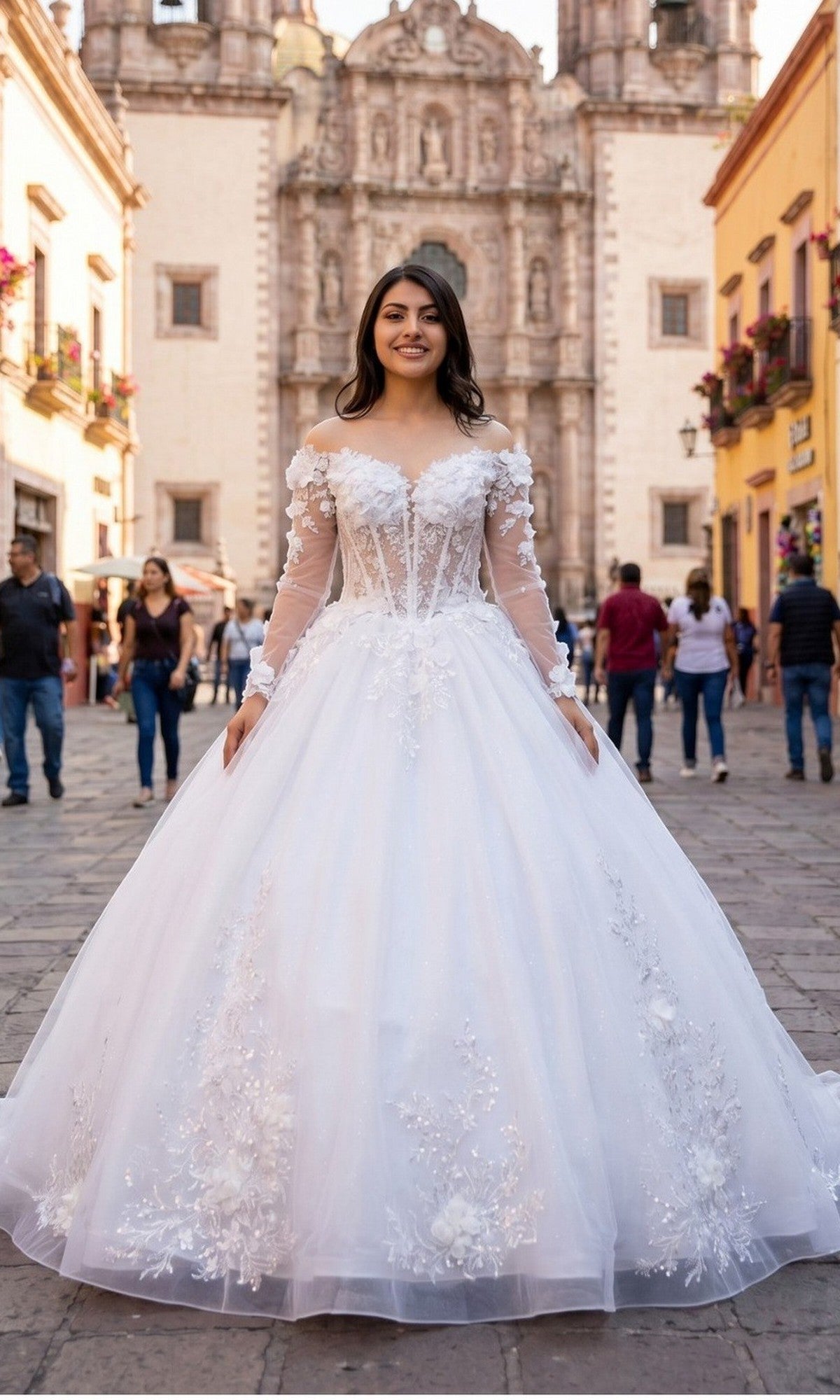 A young woman stands outdoors in the Cinderella Couture 8325J long formal dress in off white, featuring a delicate corset bodice and floral details, smiling in front of a historic stone building and colorful city street.